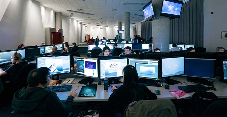 VFS 3D Animation & Visual Effects students working at high-performance computer stations in a collaborative lab environment.