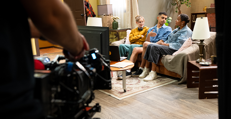 Filmmaking bootcamp participants work with a camera crew to film a scene on set. 